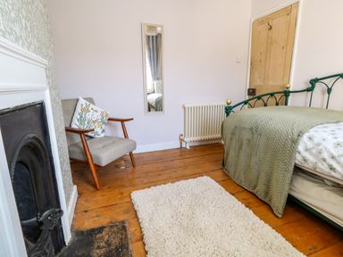 A bedroom with a bed a chair a mirror a radiator a fireplace and a rug at Georgian Hideaway in Weymouth