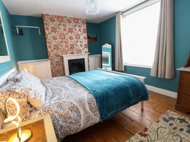 A bedroom with a bed a fireplace a mirror and a window at Georgian Hideaway in Weymouth