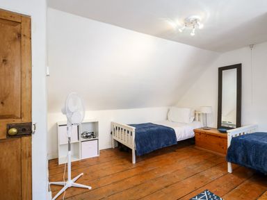 A bedroom with two single beds white shelving unit wooden chest and floor fan at Georgian Hideaway in Weymouth