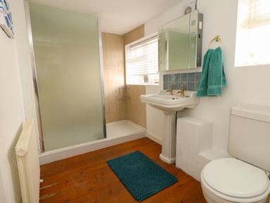A bathroom with a shower area a pedestal sink a toilet a blue mat and blue towels at Georgian Hideaway in Weymouth