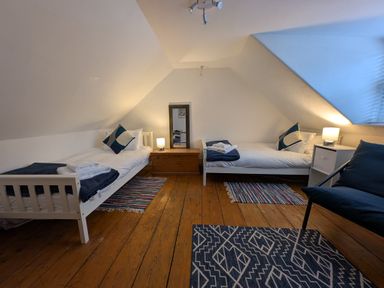 A bedroom with two single beds a wooden chest a mirror two lamps and three rugs at Georgian Hideaway in Weymouth