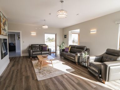 A living room with leather sofas a coffee table and large windows at Moorhen House in Loughanure near Annagry County Donegal