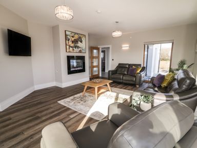A living room with leather sofas a wooden coffee table a wall-mounted TV and a fireplace at Moorhen House in Loughanure near Annagry County Donegal
