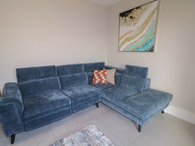 A blue sectional sofa with two cushions and a painting above in a living room at Moorhen House in Loughanure near Annagry County Donegal