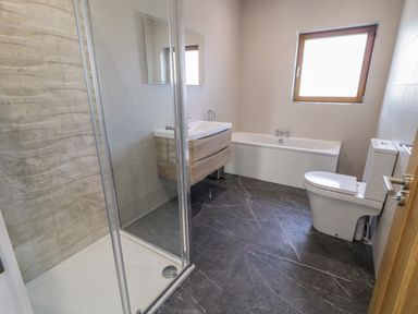 A bathroom with a shower cabin vanity with mirror bathtub and toilet at Moorhen House in Loughanure near Annagry County Donegal