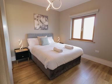 A bedroom with a double bed two bedside tables with lamps and a window at Moorhen House in Loughanure near Annagry County Donegal