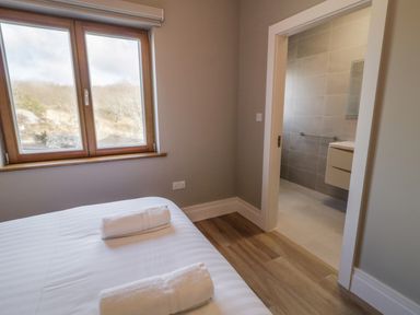 A bedroom with a bed that has two folded towels and a window showing outdoor scenery at Moorhen House Loughanure near Annagry County Donegal