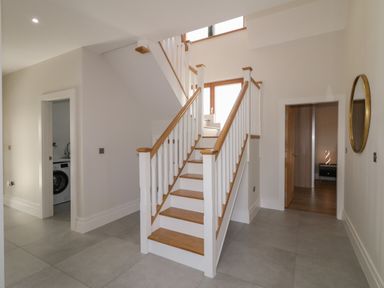 A hallway with a staircase and doors leading to a laundry room and another room at Moorhen House in Loughanure near Annagry County Donegal