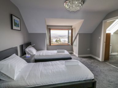 A bedroom with two single beds a nightstand and an open window showing an outdoor view at Moorhen House in Loughanure near Annagry County Donegal