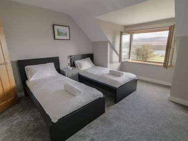 A bedroom with two single beds a nightstand and an open window showing a landscape at Moorhen House in Loughanure near Annagry County Donegal