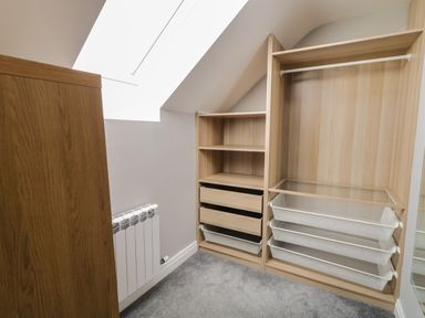 A small closet room with wooden shelving units and white baskets at Moorhen House in Loughanure near Annagry County Donegal