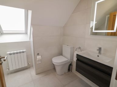 A bathroom with a toilet sink and illuminated mirror at Moorhen House in Loughanure near Annagry County Donegal