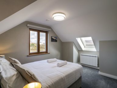 A bedroom with a bed with pillows and rolled towels near a window and skylight at Moorhen House in Loughanure near Annagry County Donegal