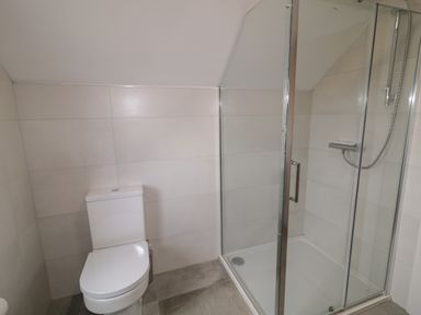 A bathroom with a toilet and a glass shower enclosure at Moorhen House in Loughanure near Annagry County Donegal