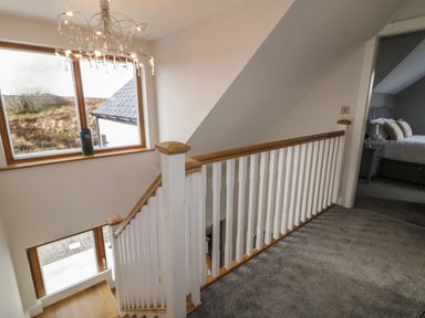 A staircase with white and wood railing next to a window and a bedroom visible at Moorhen House in Loughanure near Annagry County Donegal