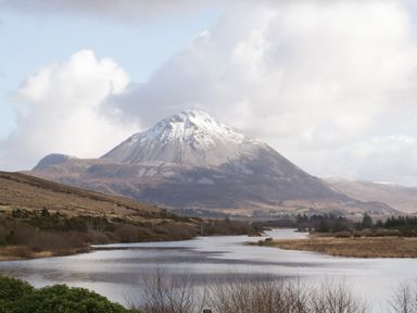 A river flowing through a valley with a snow-capped mountain in the background at Moorhen House in Loughanure near Annagry County Donegal