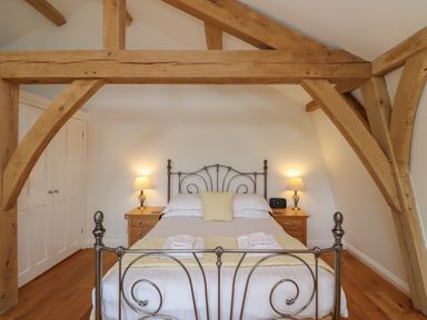 A bedroom with a metal bed frame wooden beams on ceiling and two bedside tables with lamps at The Boathouse in Belford