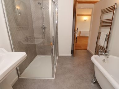 A bathroom with a glass shower enclosure a pedestal sink a towel rack with towels and a clawfoot bathtub at The Boathouse in Belford