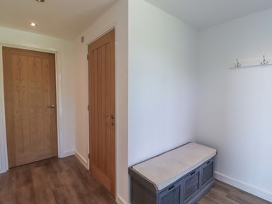 A small room with two wooden doors a cushioned bench and a coat rack at Otters Cove in Belford