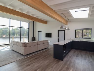 A living room with a sectional sofa and a kitchen with pendant lights and a skylight at Otters Cove in Belford