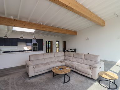 A living room with a beige sectional sofa and round wooden tables with metal legs at Otters Cove in Belford