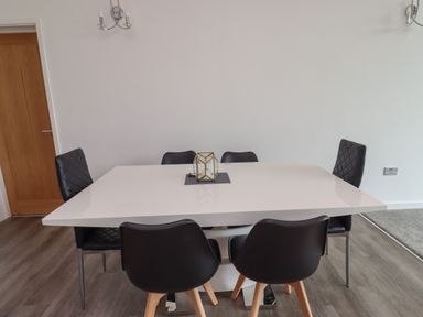 A dining area with a white rectangular table surrounded by six black chairs at Otters Cove in Belford