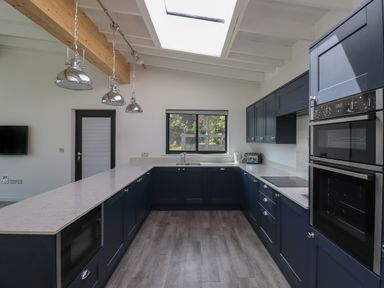A kitchen with blue cabinets a window above a sink and stainless steel appliances at Otters Cove in Belford