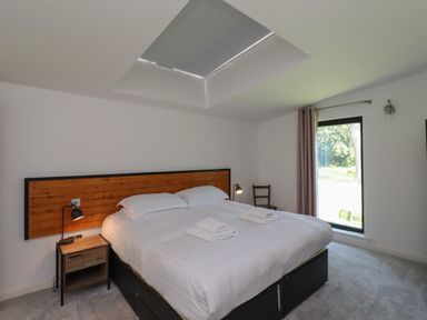 A bedroom with a double bed and towels on the bed next to a window with curtains at Otters Cove in Belford