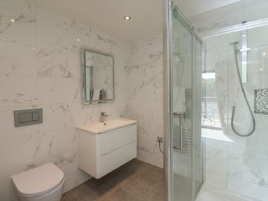 A bathroom with a wall-mounted vanity sink toilet and a glass enclosed shower at Otters Cove in Belford