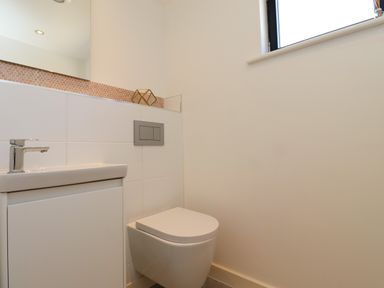 A bathroom with a toilet and a sink under a window at Otters Cove in Belford