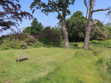 A garden area with two wooden benches and trees at Otters Cove in Belford
