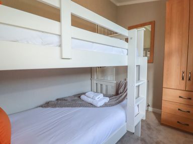 A bedroom with a white bunk bed and a wooden wardrobe at 4 Meadow Retreat in Dobwalls