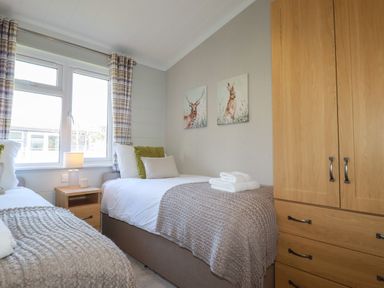 A bedroom with two single beds a wooden wardrobe and a nightstand with a lamp at 4 Meadow Retreat Dobwalls