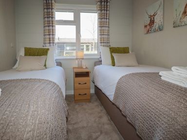 A bedroom with two single beds a nightstand with a lamp and paintings on the wall at 4 Meadow Retreat in Dobwalls