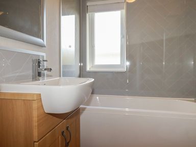 A bathroom with a sink on a wooden cabinet a bathtub a window and tiled walls at 4 Meadow Retreat in Dobwalls