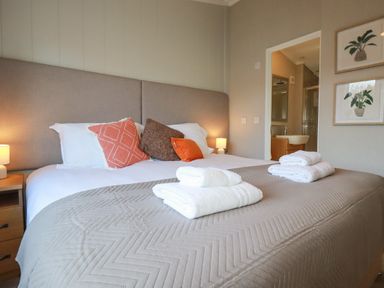 A bedroom with a bed with pillows and folded towels with an adjoining bathroom at 4 Meadow Retreat in Dobwalls