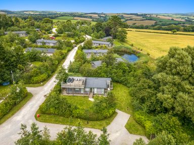 An aerial view of a rural area with small houses surrounded by trees and fields at 4 Meadow Retreat in Dobwalls