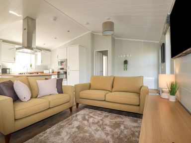 A living room with two sofas a rug a wooden table a lamp and an open kitchen at 23 Meadow Retreat in Dobwalls