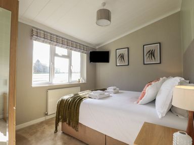 A bedroom with a bed folded towels two framed wall arts a table lamp and a window at 23 Meadow Retreat in Dobwalls