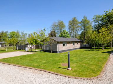A single story building on a grassy lot with trees and gravel pathways at 23 Meadow Retreat in Dobwalls