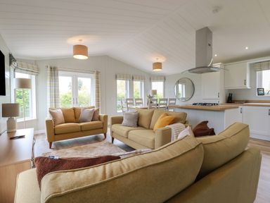 An open living and kitchen area with sofas dining table and kitchen island at 6 Faraway Fields in Dobwalls