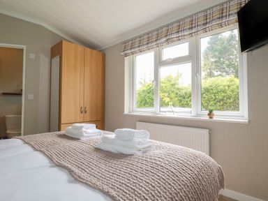 A bedroom with a bed folded towels wardrobe and a window at 6 Faraway Fields in Dobwalls