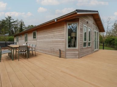 A wooden house with a large deck and outdoor dining table and chairs at 6 Faraway Fields in Dobwalls