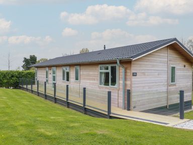 A wooden single-story house with a ramp and glass railings on a lawn at 6 Faraway Fields in Dobwalls