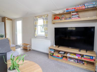 A living room with a flat screen television board and board games at Windermere Lodge in Morecambe
