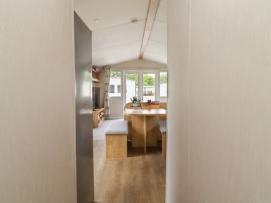 A dining area with a wooden table and bench seating inside a caravan at Windermere Lodge in Morecambe