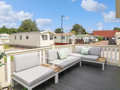 A patio with outdoor seating and cushions overlooking a mobile home park at Windermere Lodge in Morecambe
