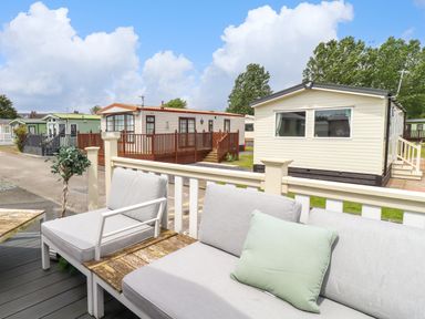 A deck with outdoor seating and mobile homes in the background at Windermere Lodge in Morecambe