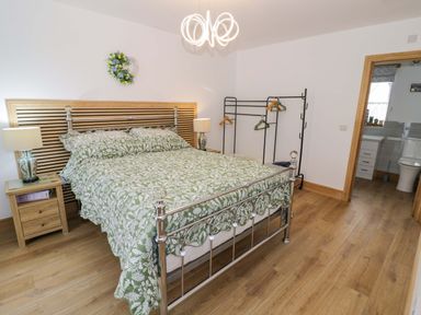 A bedroom with a bed and clothes rack at The Barn in Astwood Bank