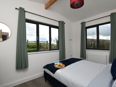 A bedroom with a bed and green curtains on windows at Cae Pren in New Mills near Llanfair Caereinion